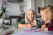© Rido - Grandmother teaching to granddaughter at home