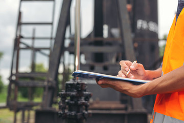 Workers standing and checking beside working oil pumps.