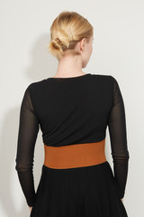 Wall Mural - Cropped back view shot of a blond girl, posing on a white background. She is wearing black gown with transparent sleeves and brown wide belt. Her hair pulled back with bobby pins. 