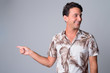 © Ranta Images - Portrait of happy handsome Hispanic tourist man pointing finger while looking away