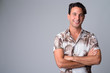© Ranta Images - Portrait of happy handsome Hispanic tourist man thinking with arms crossed