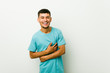 © Asier - Young hispanic man laughs happily and has fun keeping hands on stomach.