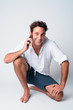© Ranta Images - Full body shot of happy handsome Hispanic man talking on the phone while crouching