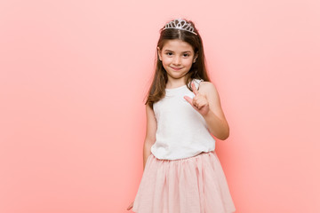 Wall Mural - Little girl wearing a princess look pointing with finger at you as if inviting come closer.