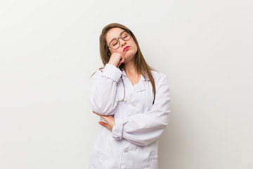 Wall Mural - Young doctor woman against a white wall who feels sad and pensive, looking at copy space.