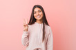 © Asier - Young pretty arab woman wearing a casual sport look joyful and carefree showing a peace symbol with fingers.