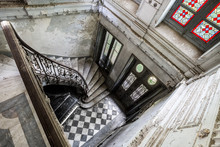 Wide Angle View Of The Marble Staircase Of An Old And Abandoned French Gentry Countryhouse With Stained-glass Windows And A Grand Piano On The Ground Floor