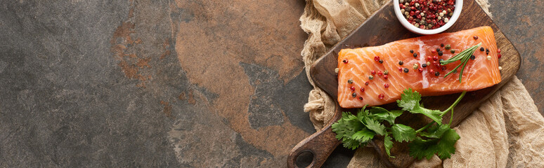 top view of raw fresh salmon with peppercorns, parsley on wooden cutting board on rustic cloth, panoramic shot