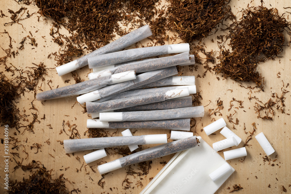 Hand rolling tobacco on a wood table Stock Photo