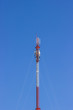 Red and white Telecommunication tower in a day of clear blue sky.