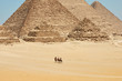 Tourists on camels are seeing Khufu, Khafre, Menkaure and pyramids of Queens