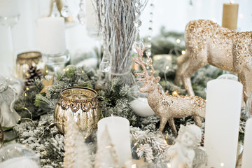 Wall Mural - New Year's festive glass table setting. Greeting card. There are wine glasses and cutlery in the branches of the Christmas tree. Decorated with gold candles, deer, stars, balls. Copy space, bokeh fir