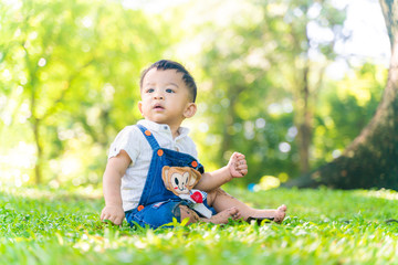 Infant baby boy playing on green meadow city park