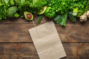 Wall Mural - Shopping bag with green vegetables on wooden background Purchase healthy food