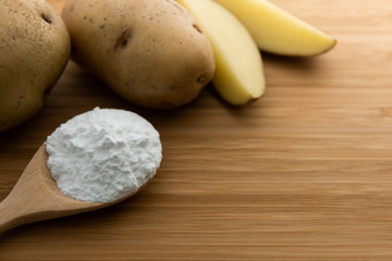 Wall Mural - Close-up of potato starch or flour powder in wooden spoon on wooden table background