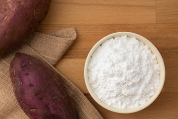 Wall Mural - Top view of sweet potato starch in white bowl with sweet potato wooden table background