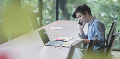 Wall Mural - young ux web developer working on laptop computer while having a phone call
