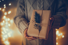 Hands In Sweater With Gift In Craft Paper, Branch