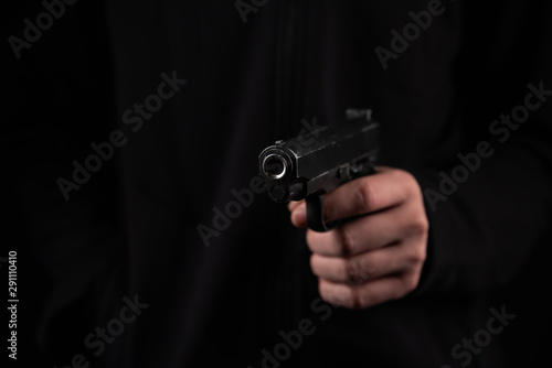 Fotomural Gun in hand on black background