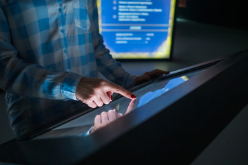 Woman using interactive touchscreen display of electronic multimedia terminal at modern museum or exhibition. Education, futuristic and technology concept