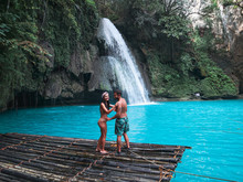 Travel Couple Alone On The Bamboo Raft In Front Of The Waterfall With Turquoise Water In Kawasan Falls In Cebu Island, Philippines