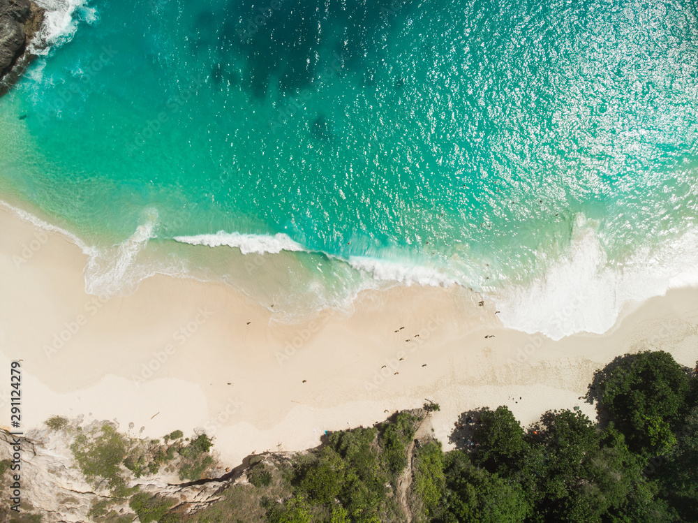 Aerial drone view of beach with waves and people at Karang Dawa, Manta Bay or Kelingking Beach on Nusa Penida Island, Bali, Indonesia - obrazy, fototapety, plakaty 