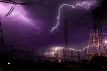 High Voltage Electrical Substation Illuminated By Lightning Flashes During An Impending Storm At Night