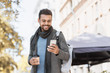 © kite_rin - Young handsome student man using smartphone. Smiling joyful guy autumn portrait. Cheerful men wearing warm clothes holding mobile phone in a city in winter.