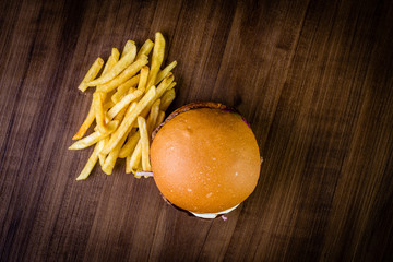 Craft beef burger with cream cheese, purple onion, jalapeno pepper and french fries  on wood table and rustic background.