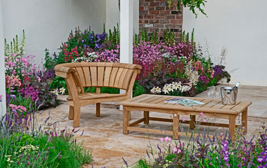 Wall Mural - A contemporary garden with terraced area and stylish wooden furniture surrounded by colourful flowering borders