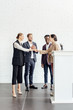 © LIGHTFIELD STUDIOS - four multiethnic colleagues in formal wear talking and shaking hands