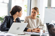 © LIGHTFIELD STUDIOS - two businesswomen in formal wear at table looking at each other during conference in office