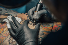 Close Up Tattoo Machine. Tattooing. Man Creating Picture On His Back By A Professional Tattoo Artist.