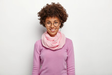 Happy Curly Woman Wears Spectacles And Violet Clothes, Enjoys Awesome Day, Smiles Gently, Poses Against White Background, Expresses Good Emotions, Comes On Job Interview. Human Face Expressions