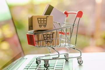 Shopping online concept - Parcel or Paper cartons with a shopping cart logo and credit card in a trolley on a laptop keyboard. Shopping service on The online web. offers home delivery..