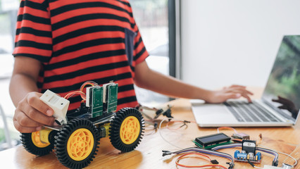 Boy with tablet pc computer programming electric toys and building robots.
