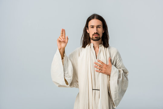 handsome bearded man praying with hand on chest isolated on grey