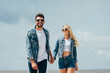 © LIGHTFIELD STUDIOS - attractive woman and handsome man in denim jackets smiling and holding hands outside