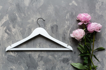 Wall Mural - white wooden hanger and pink peony flowers on gray concrete background. Fashion feminine blog sale store promo design shopping concept. Flat lay, top view, mockup, overhead