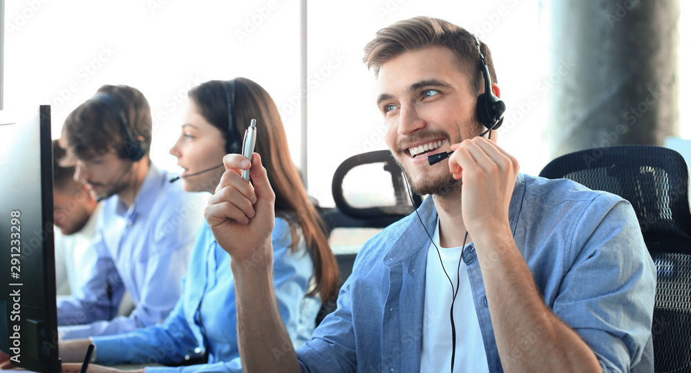 Portrait of call center worker accompanied by his team. Smiling customer support operator at work. - obrazy, fototapety, plakaty 