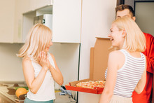 Two Young Caucasian Woman Receiving Pizza From Delivery Man At Home