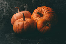 Photo Of Four Orange Pumpkins On Black Background, Halloween Celebration, Space For Inscription.