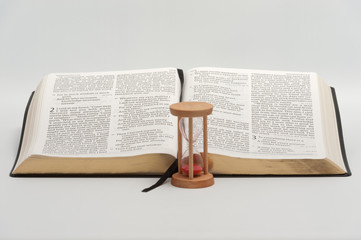 Holy Bible (Word of GOD) opened in Ecclesiastes 2 and 3 with hourglass. Isolated on white background. Horizontal shot.