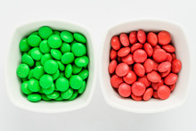 Two Squared Bowls With Small Green And Red Coated Chocolate Candies Similar To M&ms In A Squared Bowl Isolated On White Background, Top View