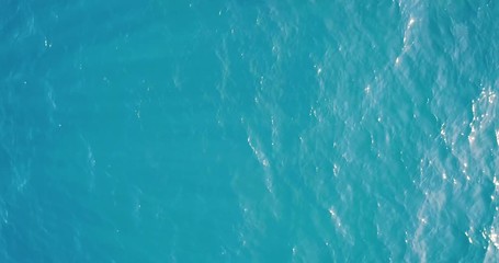 Wall Mural - Aerial top down view from high altitude of blue azure  turquoise sea water texture. The camera flies over the water, a view of the water surface. Background of the water surface. 4K aerial view