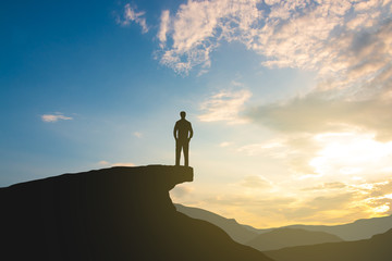 silhouette of man on mountain top over sky and sun light background,business, success, leadership, achievement and people concept