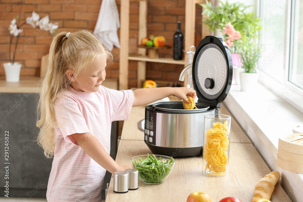 Little girl using modern multi cooker in kitchen