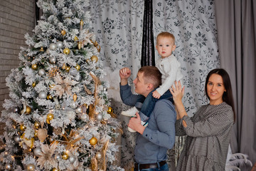 dad holds his son on his shoulders and decorate the Christmas tree with balloons