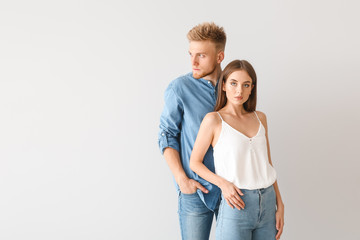 Wall Mural - Young couple in stylish casual clothes on light background