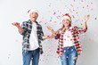 © Pixel-Shot - Portrait of happy mature couple in Santa Claus hats and with confetti on white background